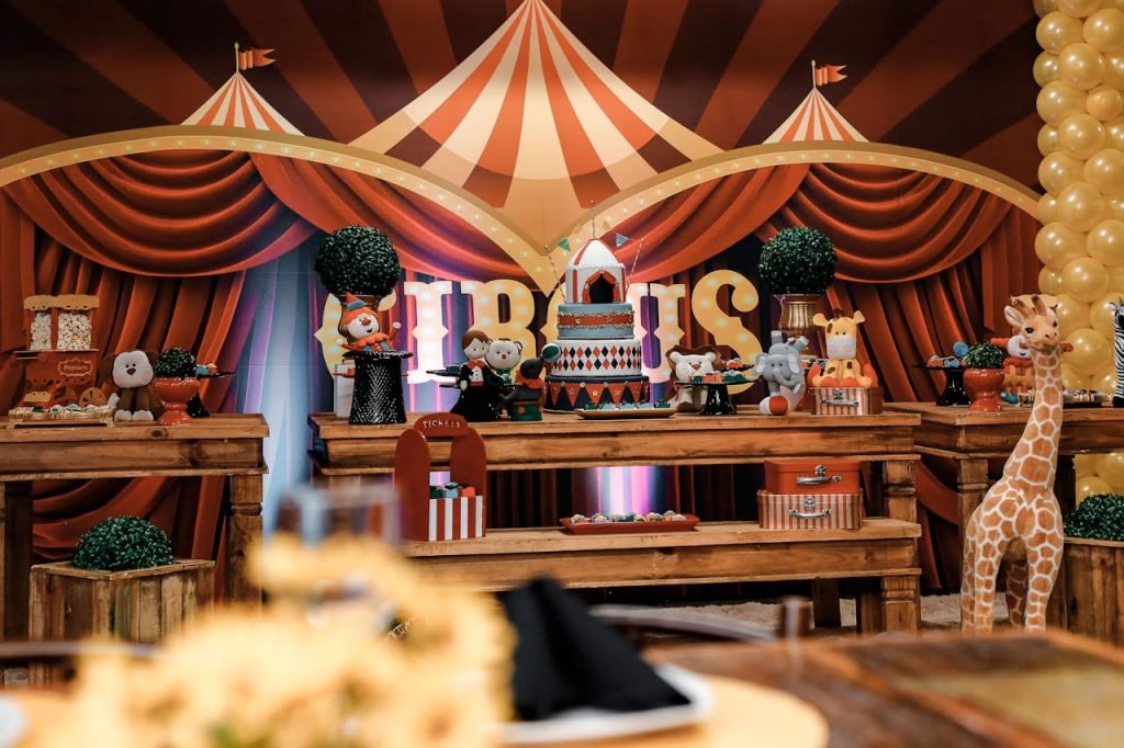 A lively circus-themed party table featuring cakes, decorations, and stuffed animals.