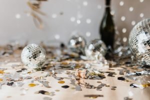 A glamorous post-party scene featuring disco balls, confetti, and a champagne bottle indoors.