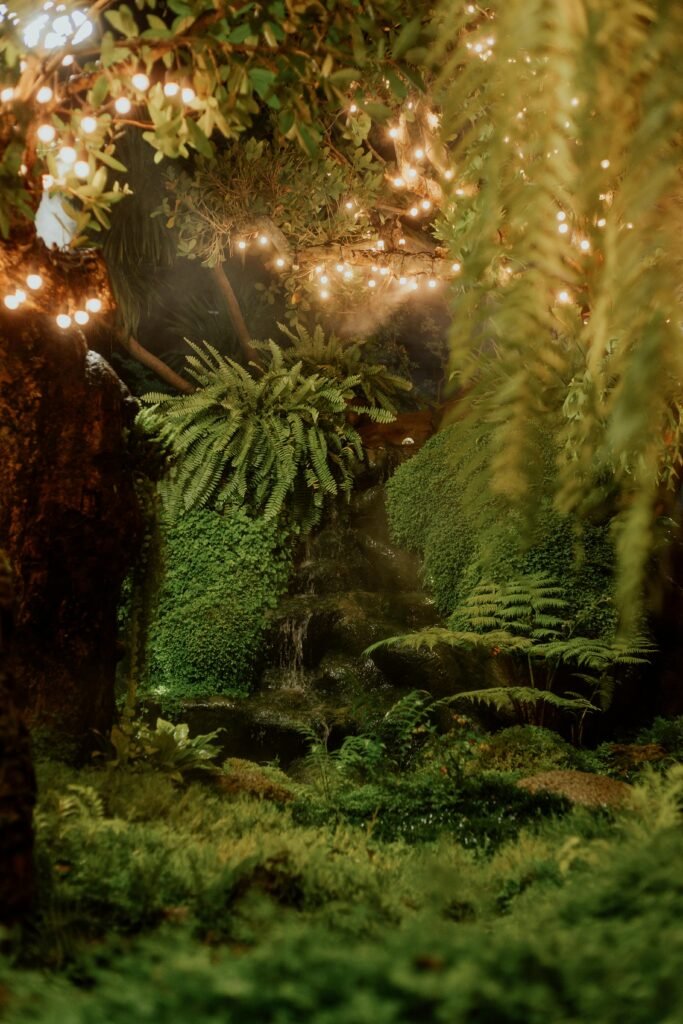 A magical forest scene with a waterfall, lush greenery, and twinkling fairy lights.